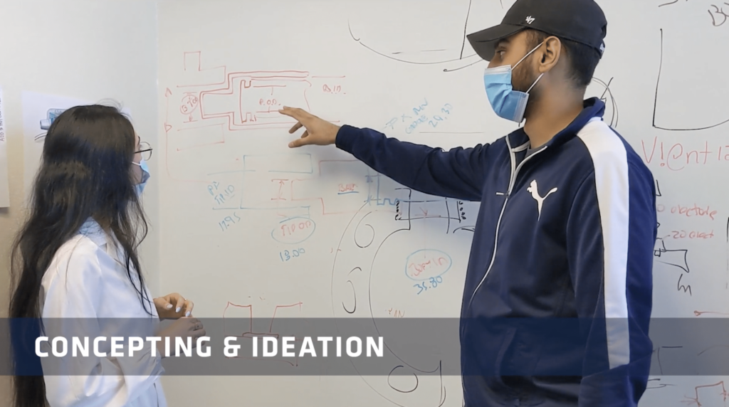 Two employees looking at a whiteboard as they discuss concepts and ideation