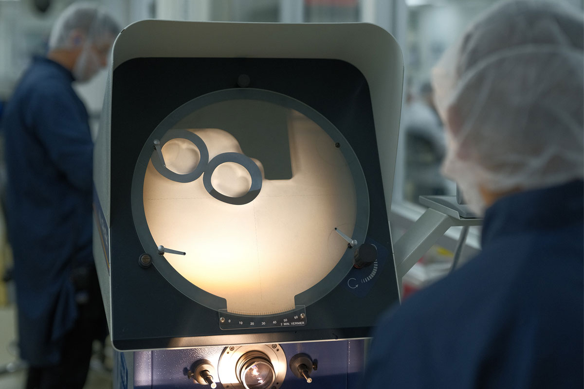 Two employees in blue lab coats working on machines.