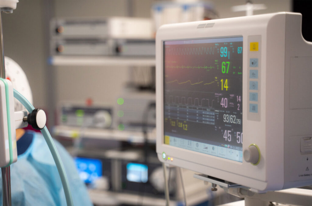 A nurse observes a monitor in an operating room.