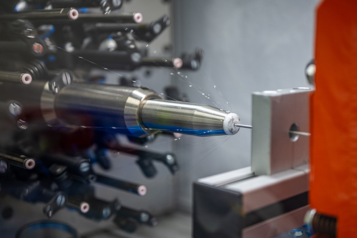 An industrial machine fabricates a metal rod within a factory setting.