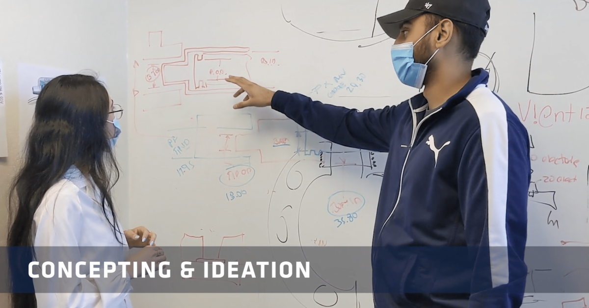 Two employees looking at a whiteboard as they discuss concepts and ideation