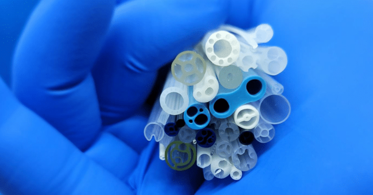 An individual holding a bundle of plastic tubes, displaying a variety of colors and shapes in their grasp.