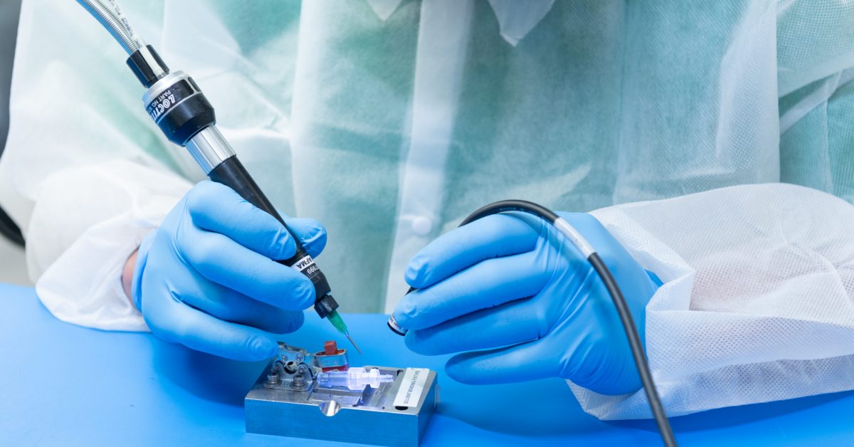 A lab-coated individual is engaged in working on a complex device in a research environment.